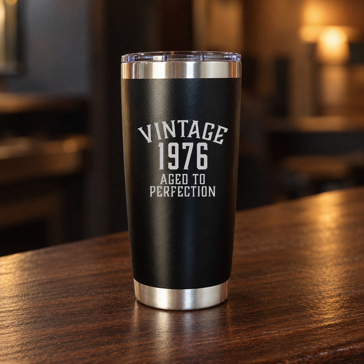 Black birthday tumbler engraved with VINTAGE, the birth year 1976 and AGED TO PERFECTION, a unique birthday gift for him on a walnut bar