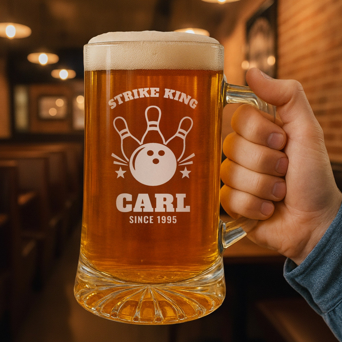 Hand holding the 25 oz personalized bowling beer mug in a pub, engraved with a bowling ball and three pins: Strike King, Carl, Since 1995
