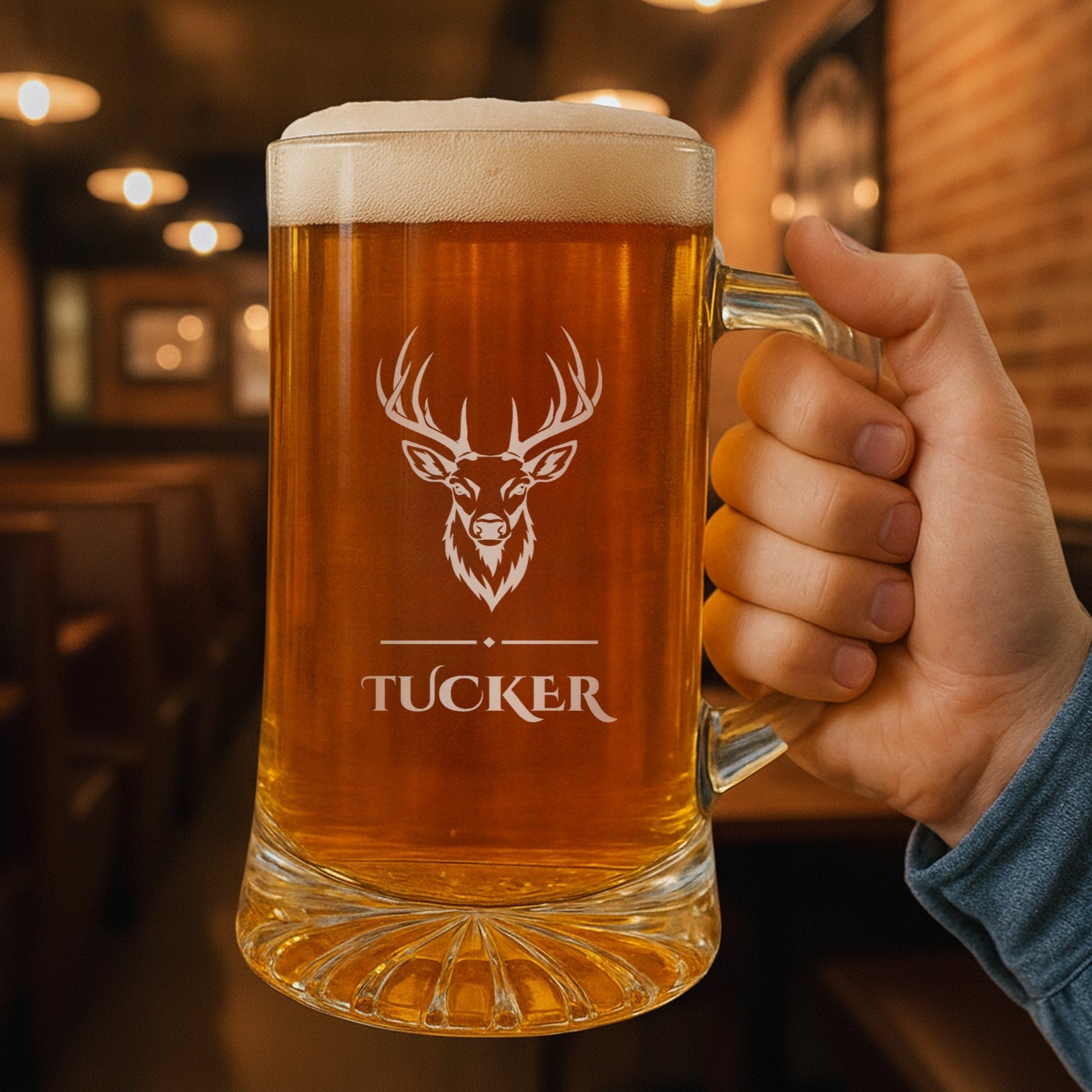Hand holding a 25 oz glass beer stein engraved with a trophy whitetail buck and the name Tucker, a personalized gift for hunters