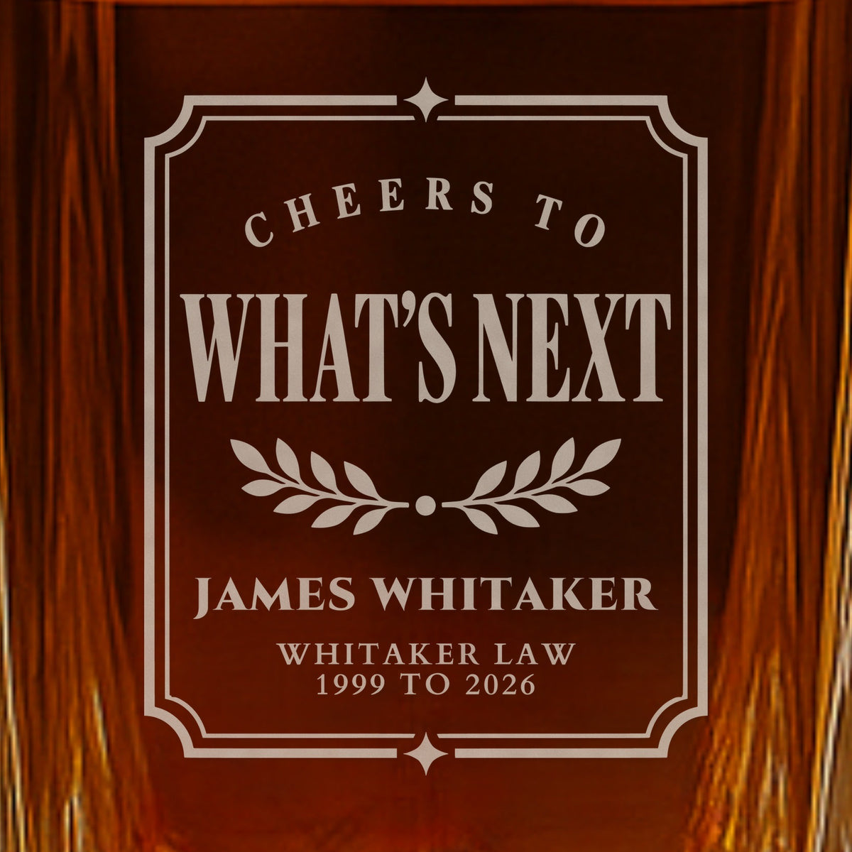 Close-up of a frosted Cheers to What's Next label engraved on a whiskey decanter, a gift for a departing boss, James Whitaker of Whitaker Law