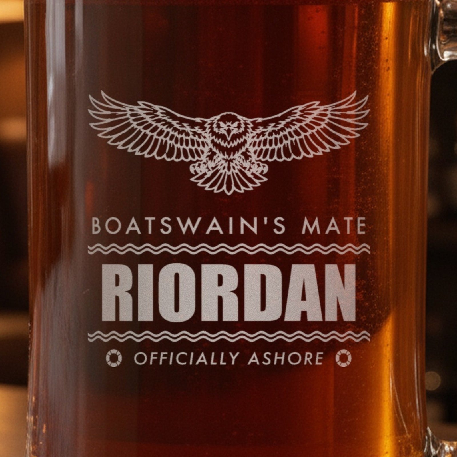Close-up of the frosted eagle engraving on a retired Coast Guard gift stein: Boatswain's Mate, Riordan between wave lines and Officially Ashore