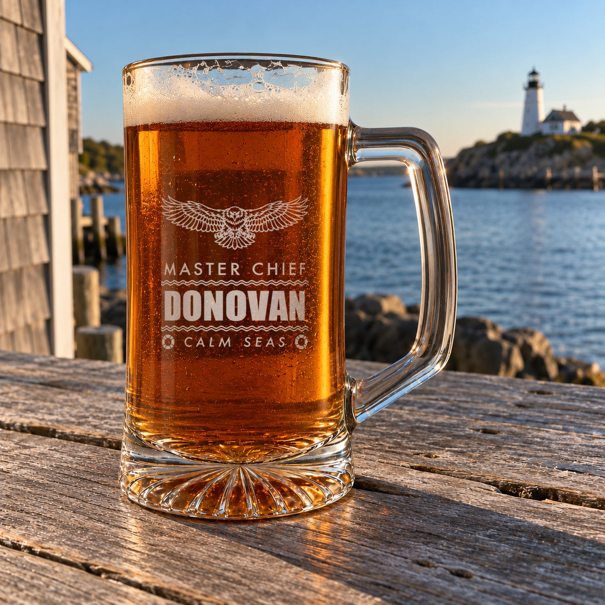 Coast Guard retirement beer stein on a harbor porch table with a lighthouse behind it, engraved with an eagle, Master Chief, Donovan and Calm Seas