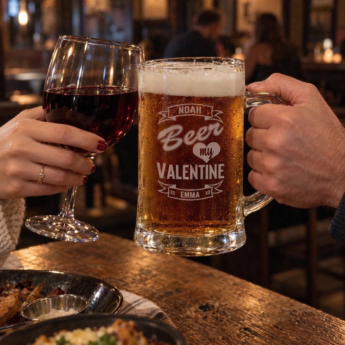 A couple toasts at a pub with a Beer My Valentine mug engraved NOAH and EMMA and a glass of wine, one of the manly valentines gifts for him