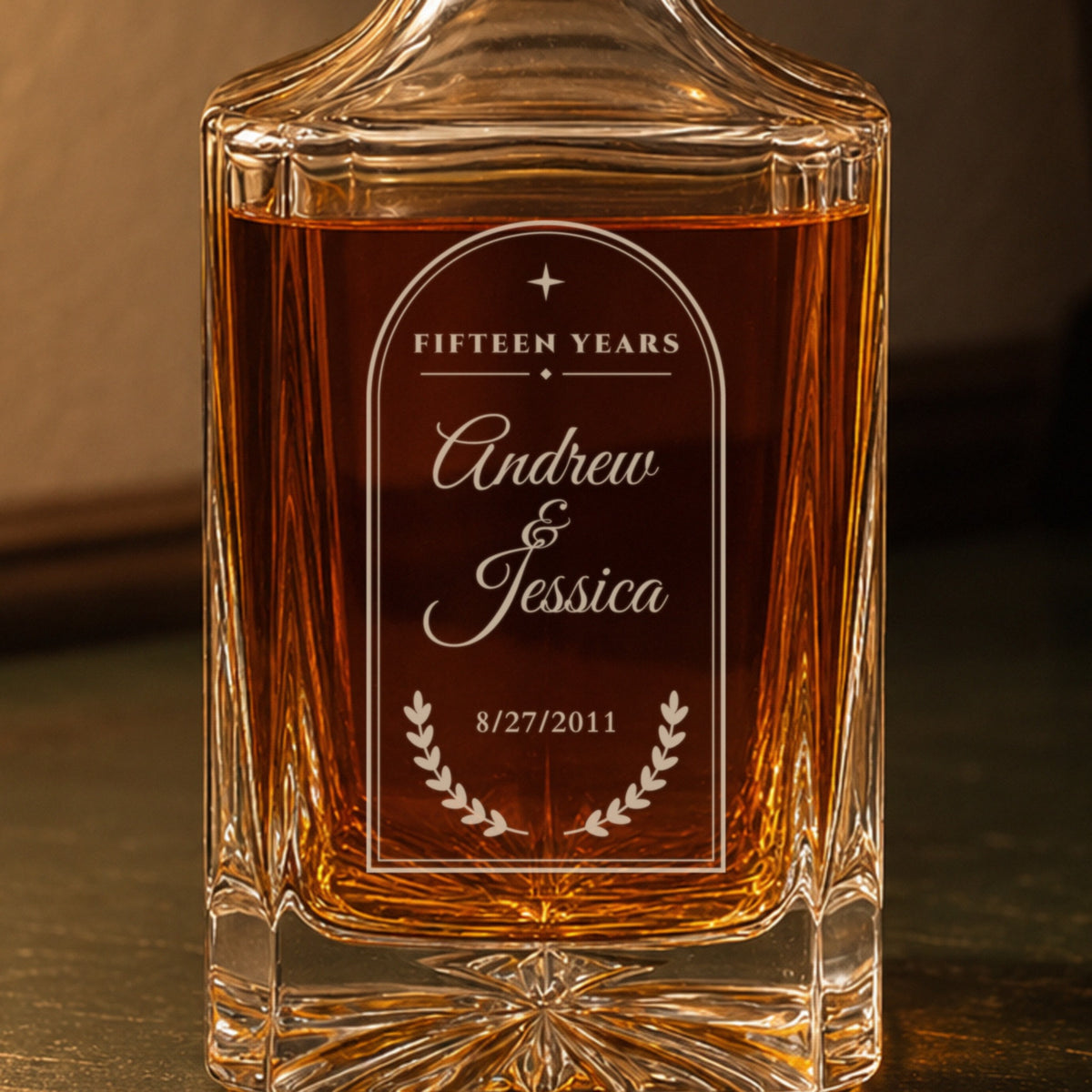 Close-up of the frosted laser engraving on a 15th anniversary decanter for husband: arched frame, Fifteen Years, Andrew and Jessica, laurel and 8/27/2011