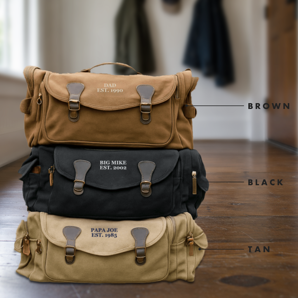 Brown, black and tan personalized dad duffle bags stacked in a mudroom, embroidered DAD EST. 1990, BIG MIKE EST. 2002 and PAPA JOE EST. 1985