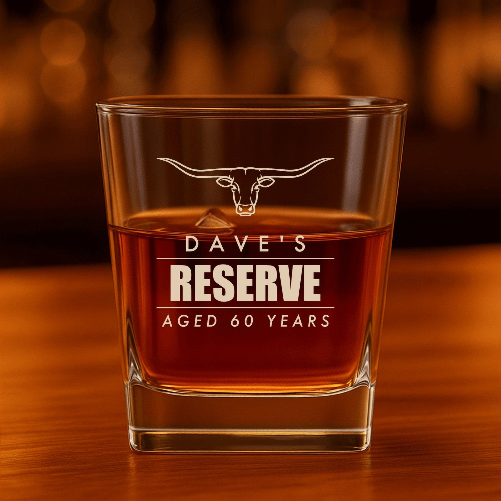 Engraved rocks glass reading Dave's Reserve, Aged 60 Years under a Texas longhorn, a personalized 60th birthday whiskey glass for him