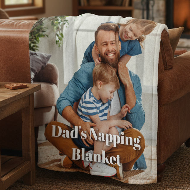 Personalized blanket draped over a tan couch featuring a photo of a father with two young children and sample text reading "Dad's Napping Blanket