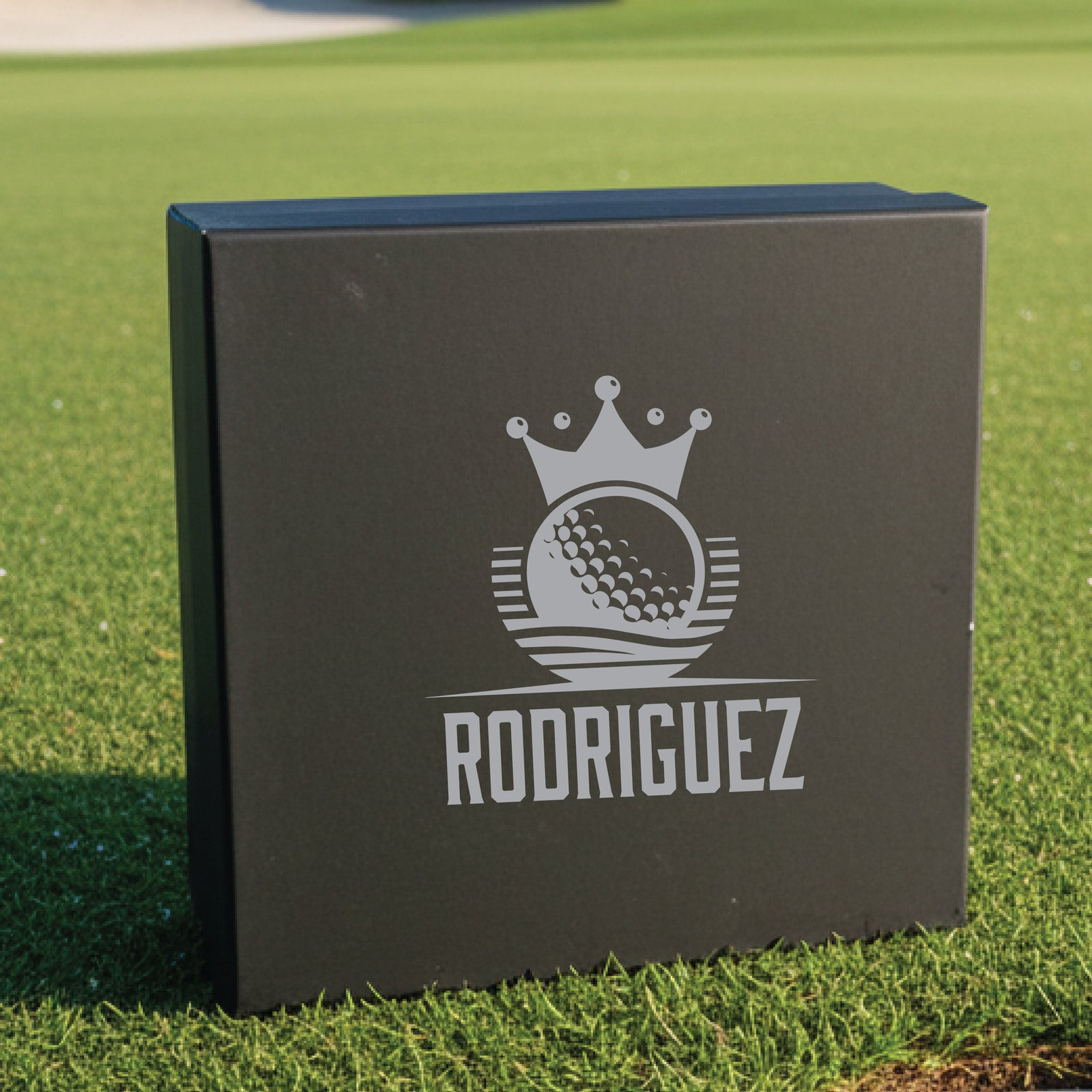 Black gift box with laser-engraved crown and golf ball logo, personalized with sample name "RODRIGUEZ" in silver lettering