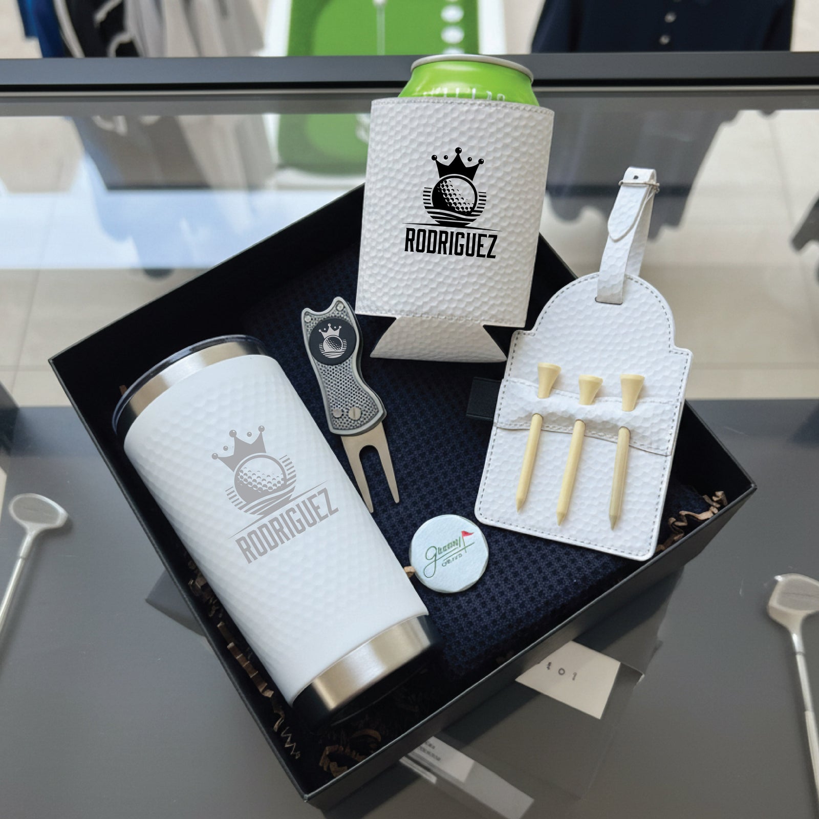 Golf gift set with personalized tumbler, can cooler, divot tool, tee holder, and ball marker all engraved with sample name "RODRIGUEZ" and crown logo