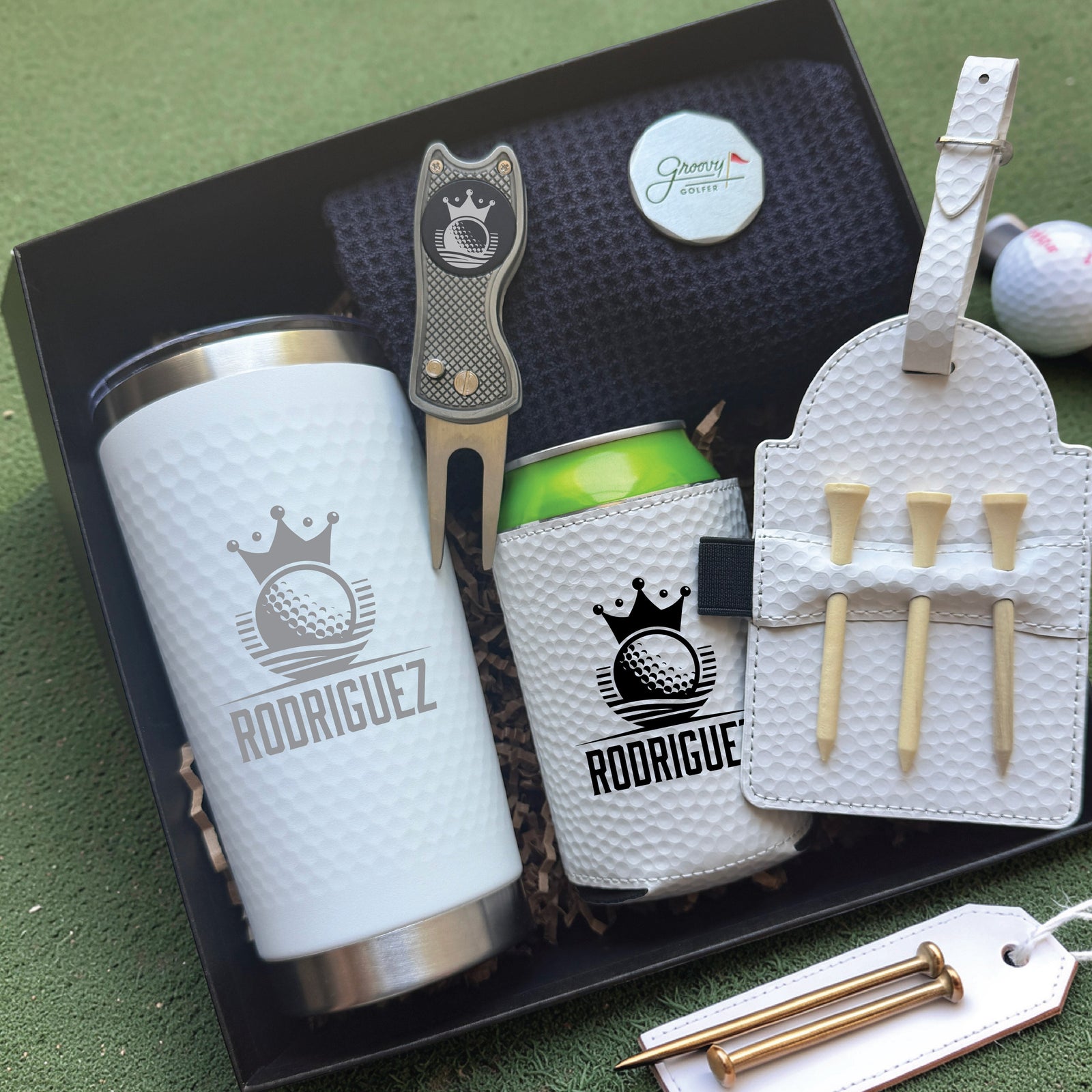 Golf-themed gift set with tumbler, can cooler, and tee holder on a green surface.