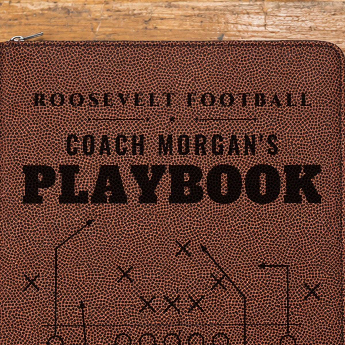Close-up of the black laser engraving on the football grain cover: Roosevelt Football, Coach Morgan's Playbook and the X's and O's play diagram