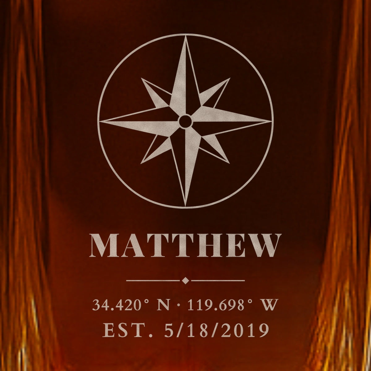 Close-up of frosted engraving on a whiskey decanter for husband: a compass rose, the name Matthew, Santa Barbara wedding coordinates and EST. 5/18/2019