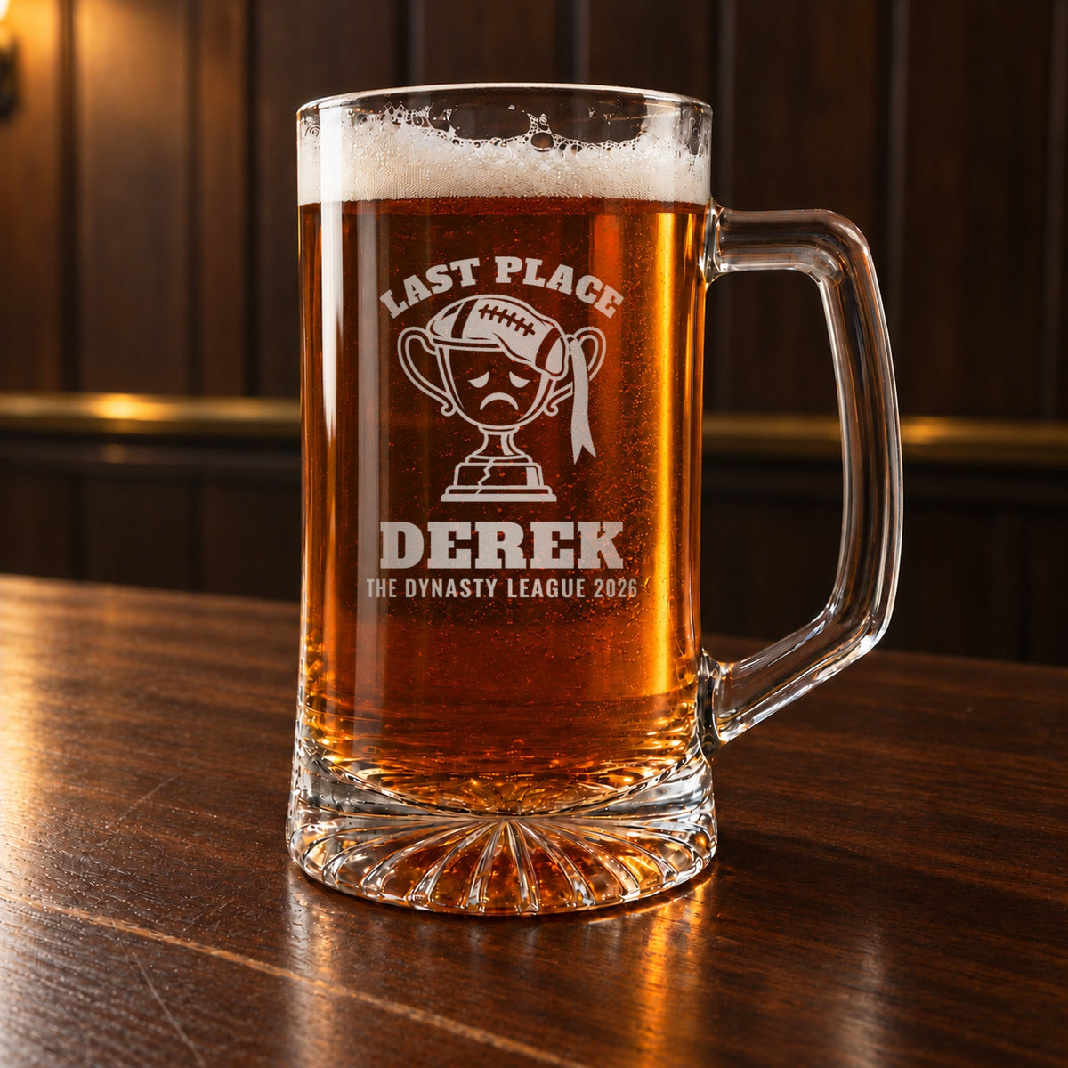 Fantasy football last place beer stein on a bar, engraved with a sad trophy wearing a flat football, Last Place, Derek and The Dynasty League 2026
