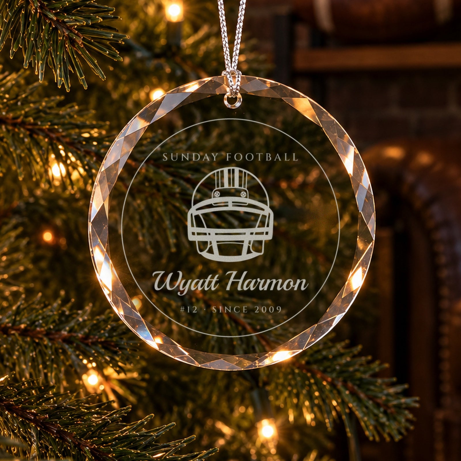 Personalized football Christmas ornament in faceted glass on a tree in a brick-walled man cave, engraved with a football helmet, SUNDAY FOOTBALL, Wyatt Harmon, #12 · SINCE 2009