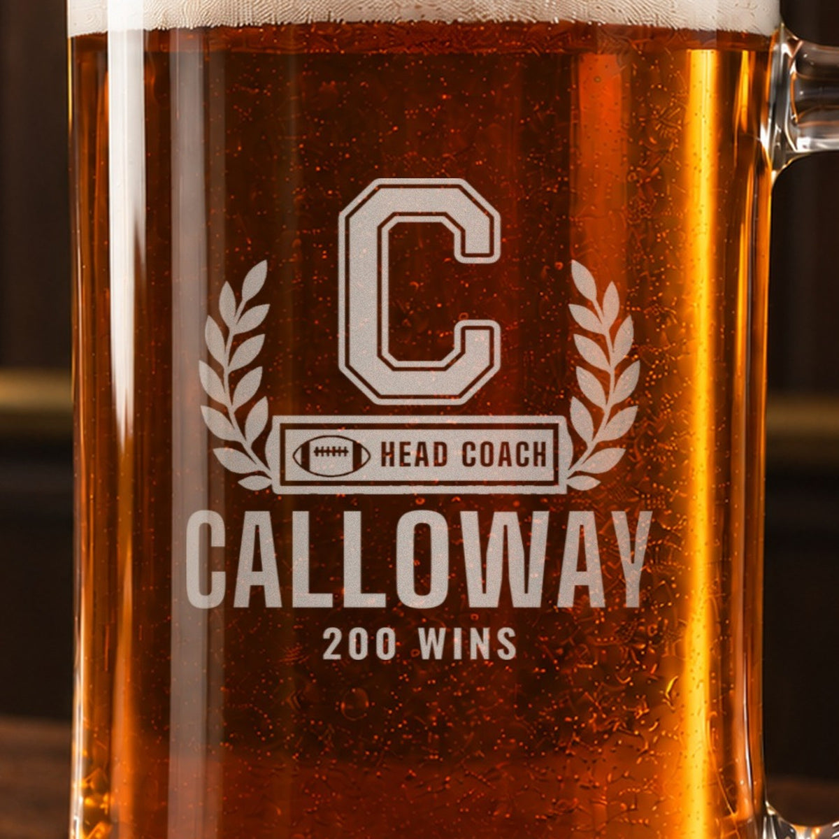 Close-up of the frosted engraving on the football coach letterman beer stein, a varsity letter with laurel and a COACH bar: C, Head Coach, Calloway, 200 Wins