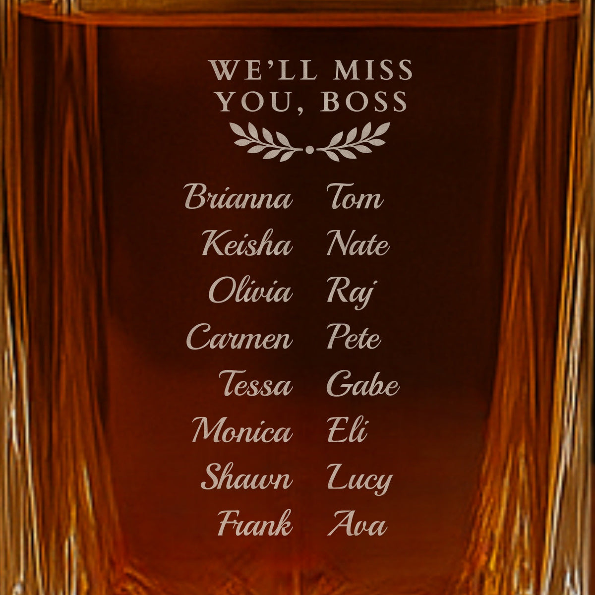 Back of a gift for a boss leaving: We'll Miss You, Boss engraved above a laurel and sixteen team names in script on a glass whiskey decanter