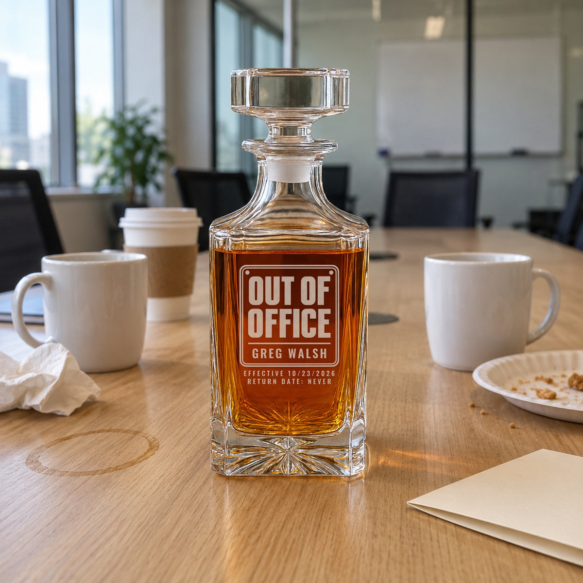 Engraved Out of Office decanter on a conference table at an office send-off with coffee mugs and a card, a going away gift for Greg Walsh