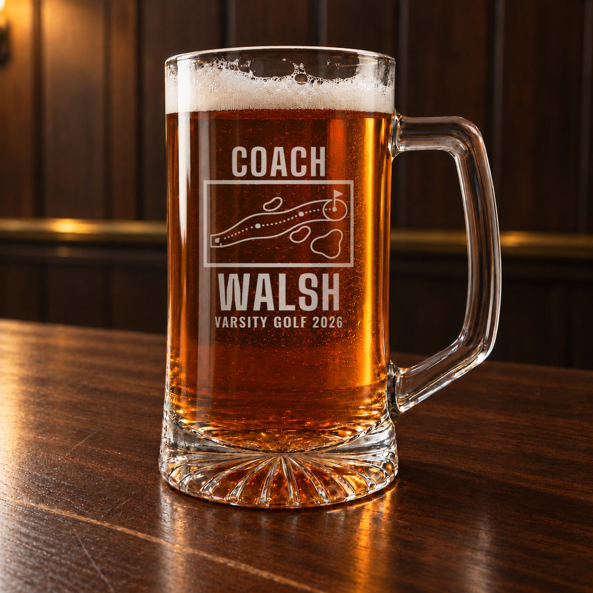 Personalized golf coach yardage book beer stein on a walnut bar, engraved with a golf hole map with tee, fairway, bunkers, water and green: Coach, Walsh, Varsity Golf 2026