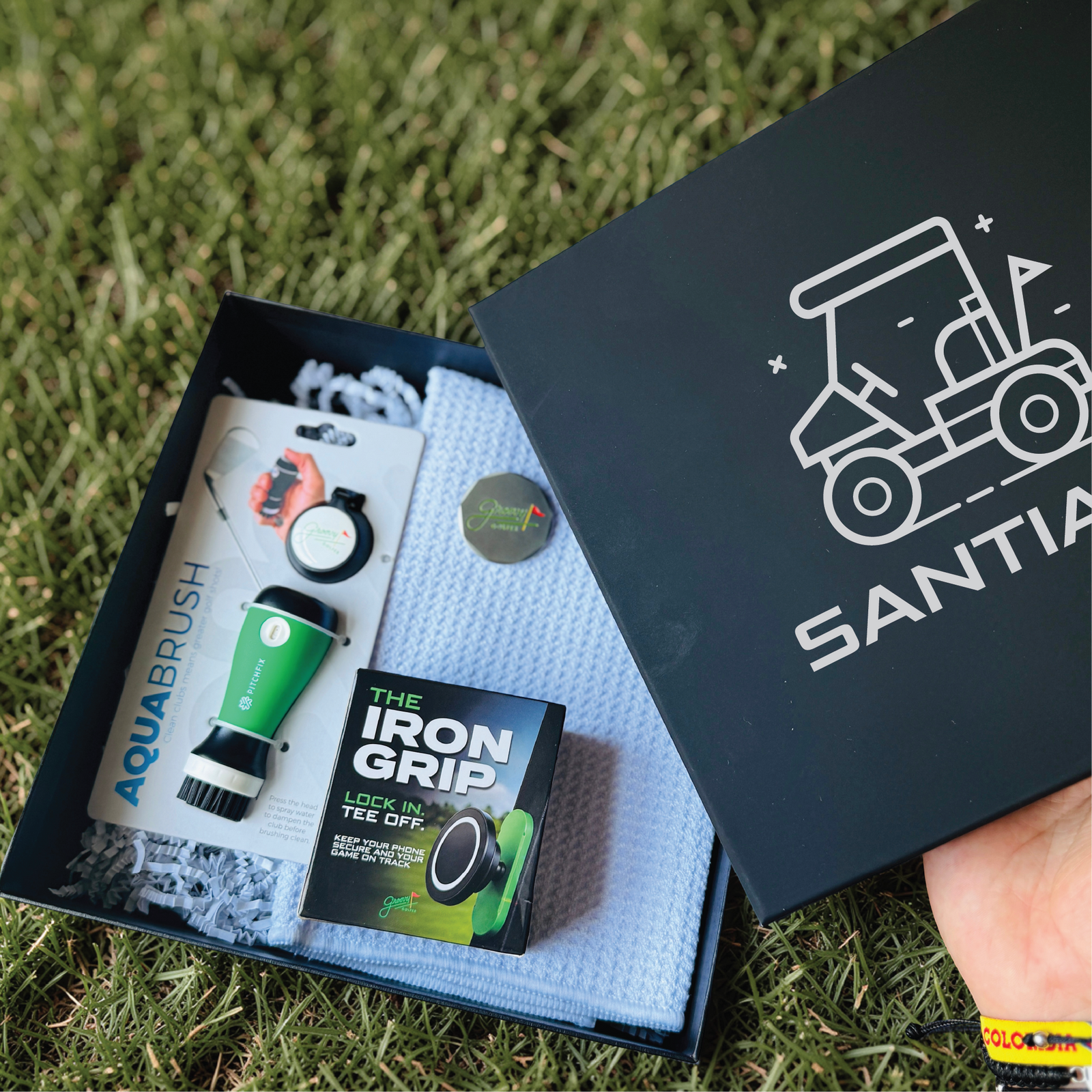 Personalized golf gift box for men with a name-engraved lid, open to show the club cleaner, waffle towel, ball marker and magnetic phone mount.