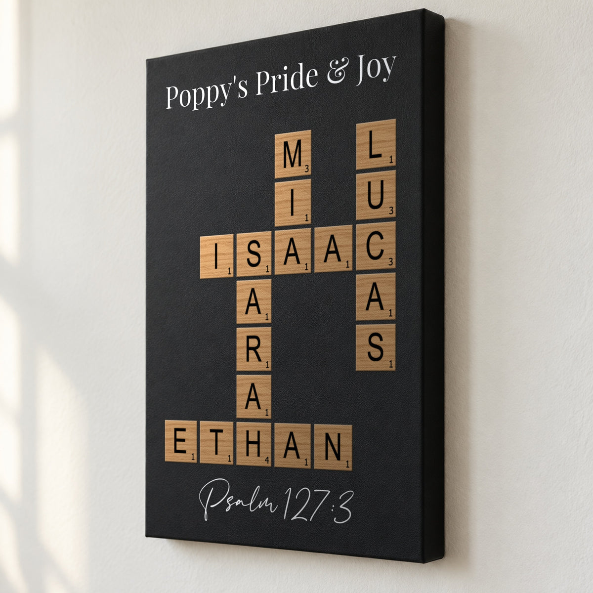 Angled close view of a Poppy's Pride and Joy crossword sign showing the 1.5 inch deep edge and grandkids' names printed flat on black leatherette
