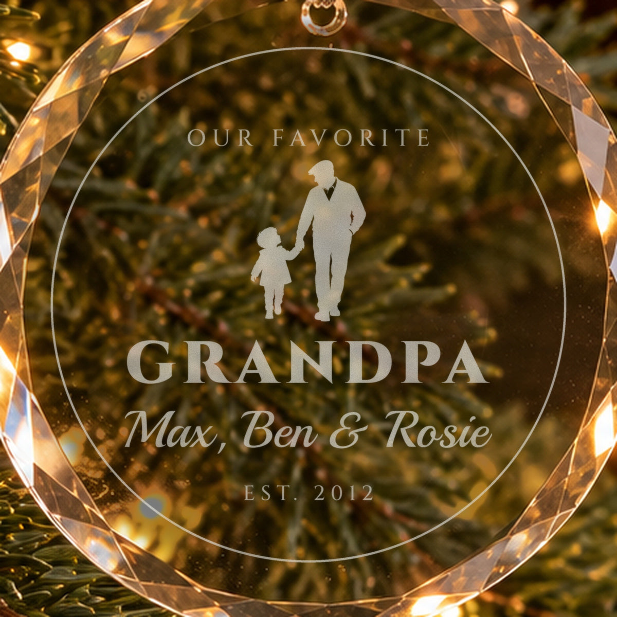 Close-up of the frosted engraving on the grandpa ornament: a grandfather walking hand in hand with a grandchild, GRANDPA, Max, Ben & Rosie, EST. 2012