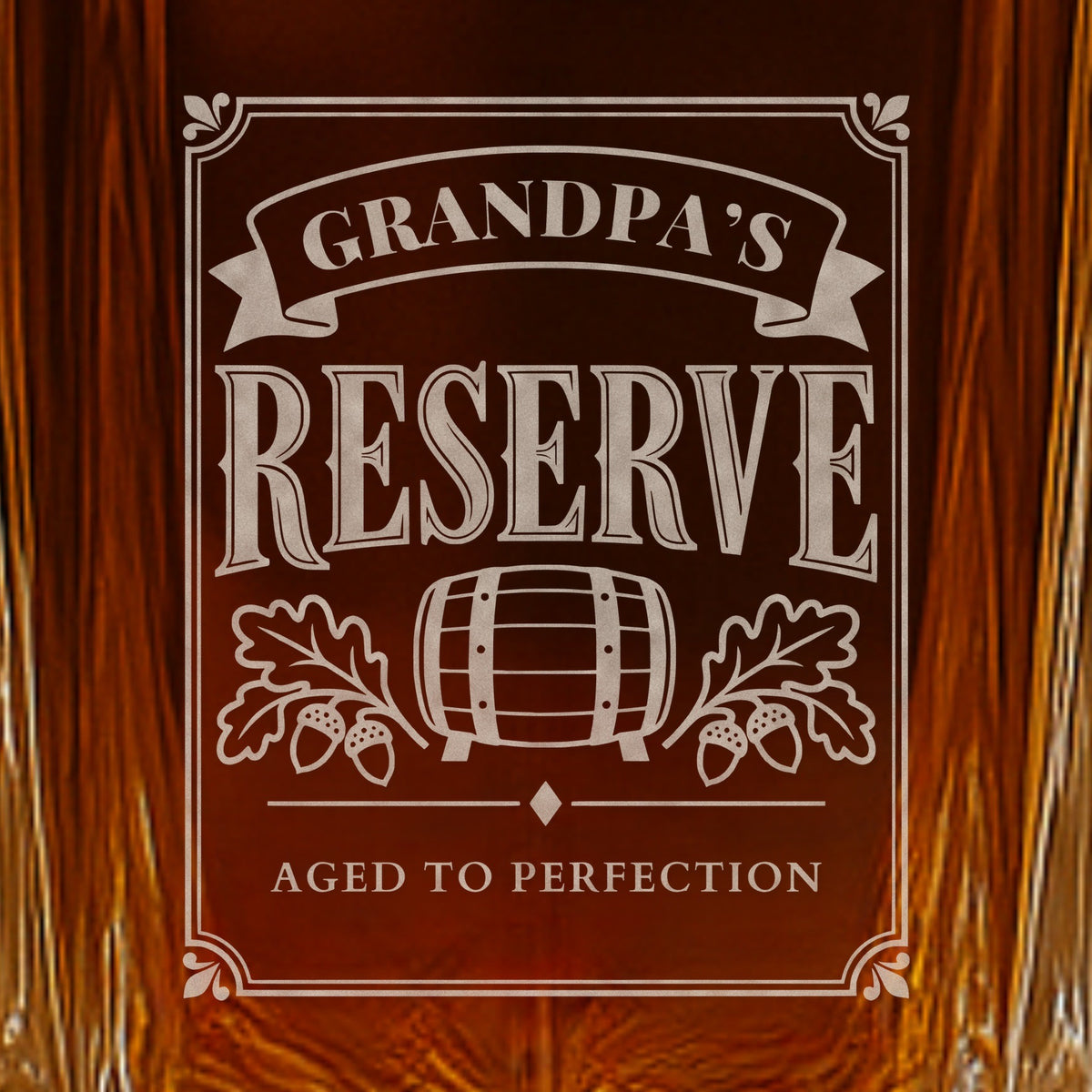 Close-up of the frosted Grandpa's Reserve engraving on a whiskey decanter: a ribbon, barrel and oak leaves over the line Aged to Perfection