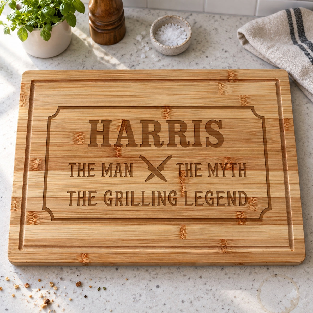 Personalized bamboo cutting board for men engraved HARRIS above THE MAN, THE MYTH, THE GRILLING LEGEND, lying on a bright kitchen counter