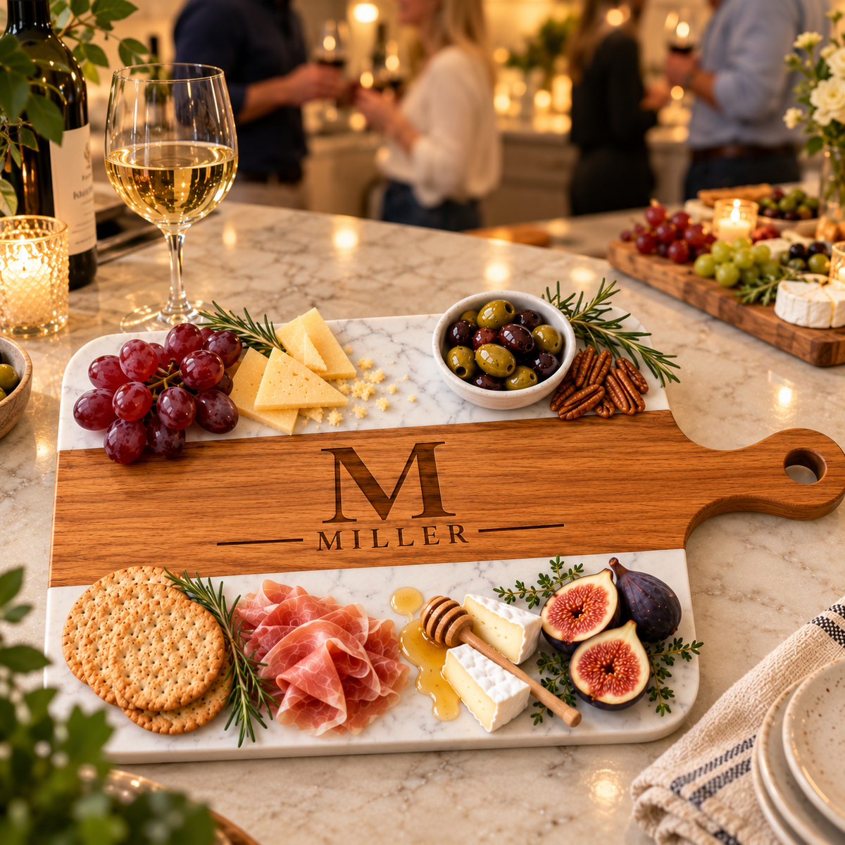 Engraved monogram serving board with M and MILLER on a marble kitchen island at an evening party with wine, a housewarming gift for the guy who loves to host