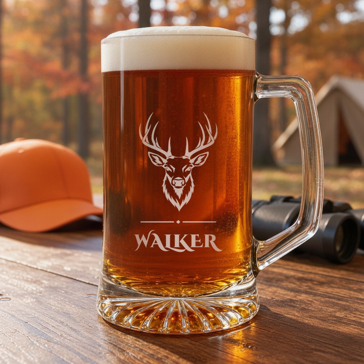 Engraved buck beer stein at deer camp beside a blaze orange cap and binoculars, personalized with the hunter's name Walker under the buck