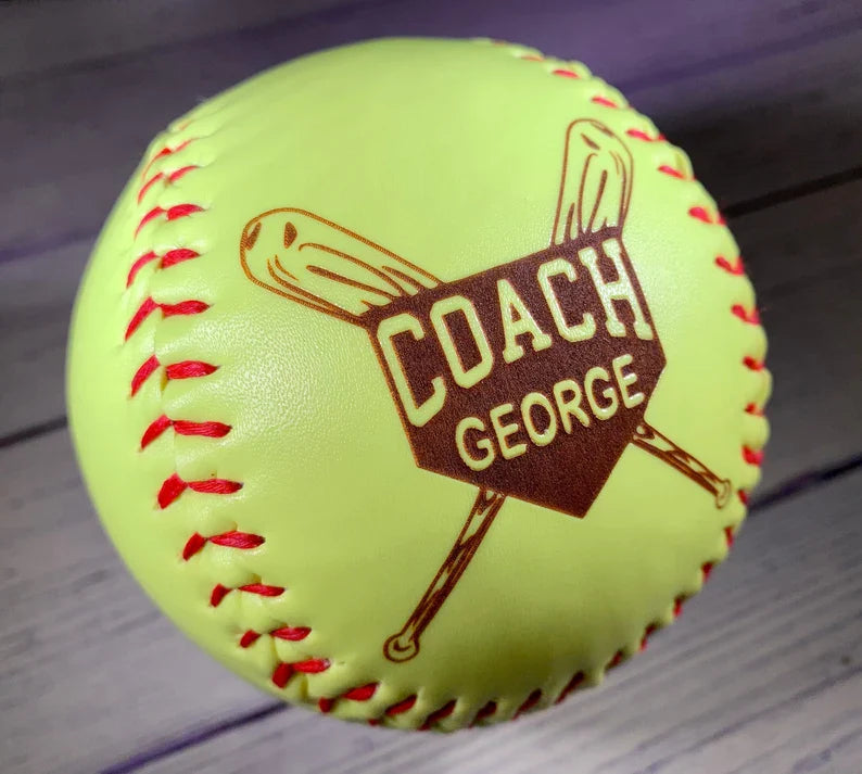 Neon yellow regulation softball with red stitching and laser engraved coach name shown at an angle for display