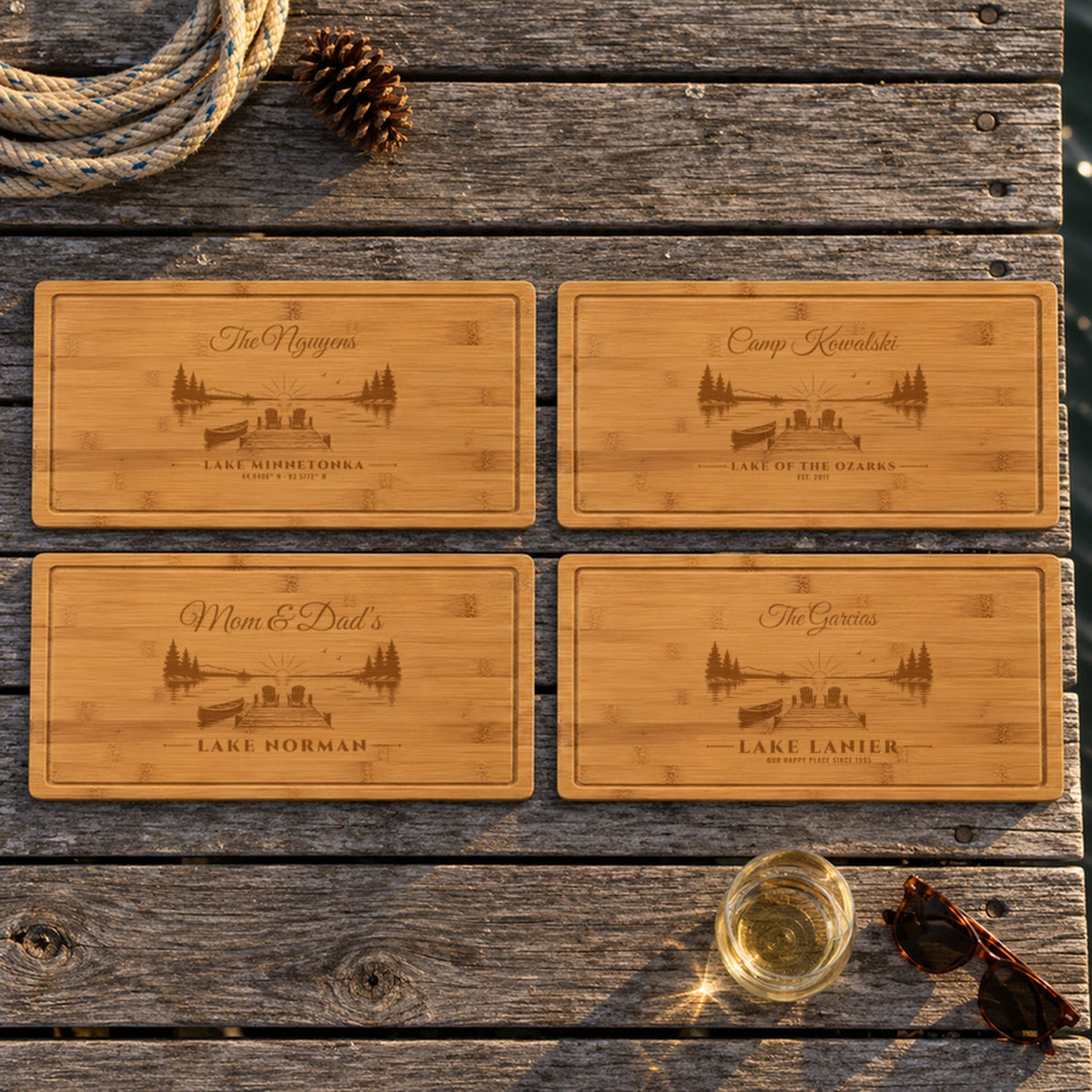Four engraved lake house cutting board ideas on a dock: The Nguyens Lake Minnetonka, Camp Kowalski Lake of the Ozarks, Mom & Dad's Lake Norman, The Garcias Lake Lanier