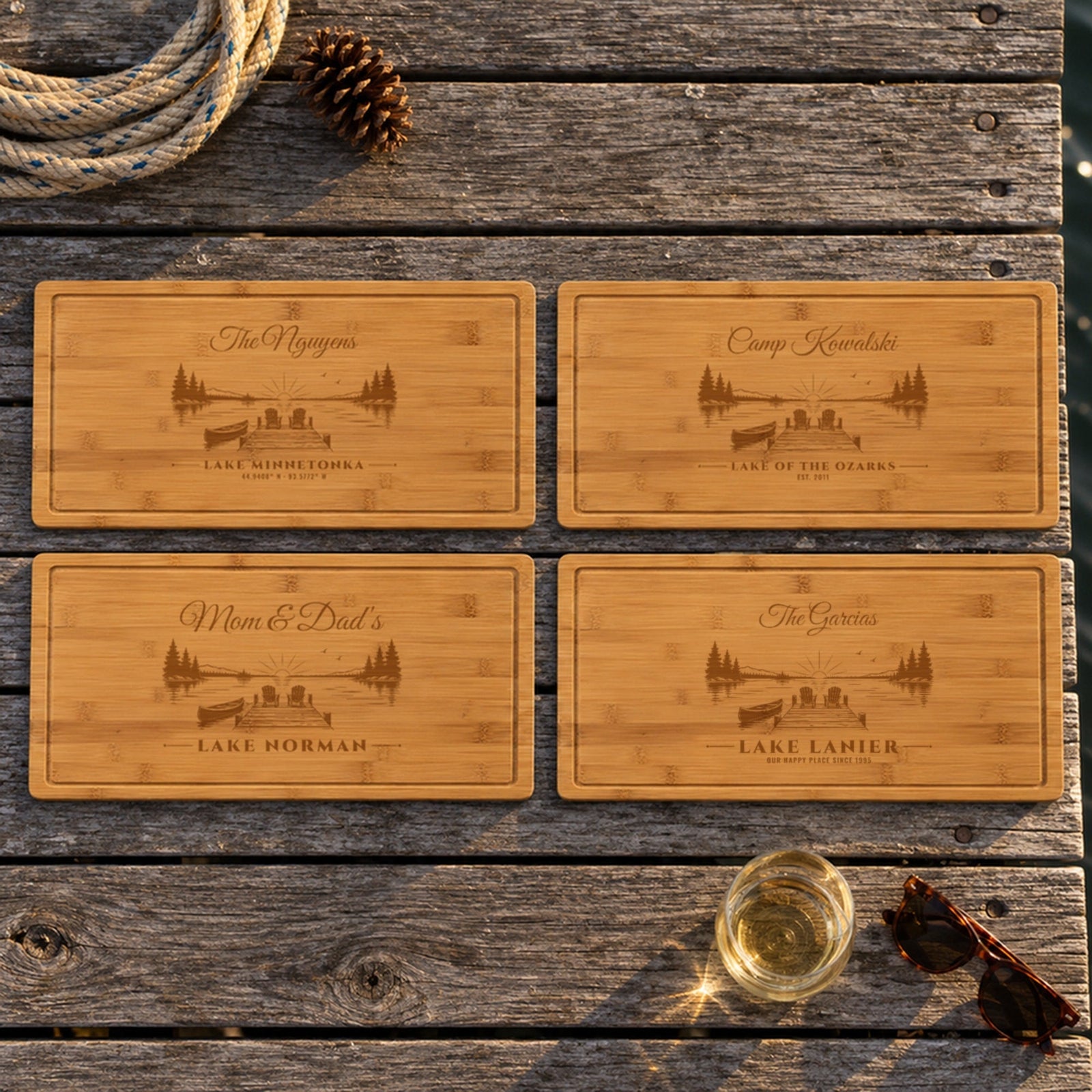 Four engraved lake house cutting board ideas on a dock: The Nguyens Lake Minnetonka, Camp Kowalski Lake of the Ozarks, Mom & Dad's Lake Norman, The Garcias Lake Lanier