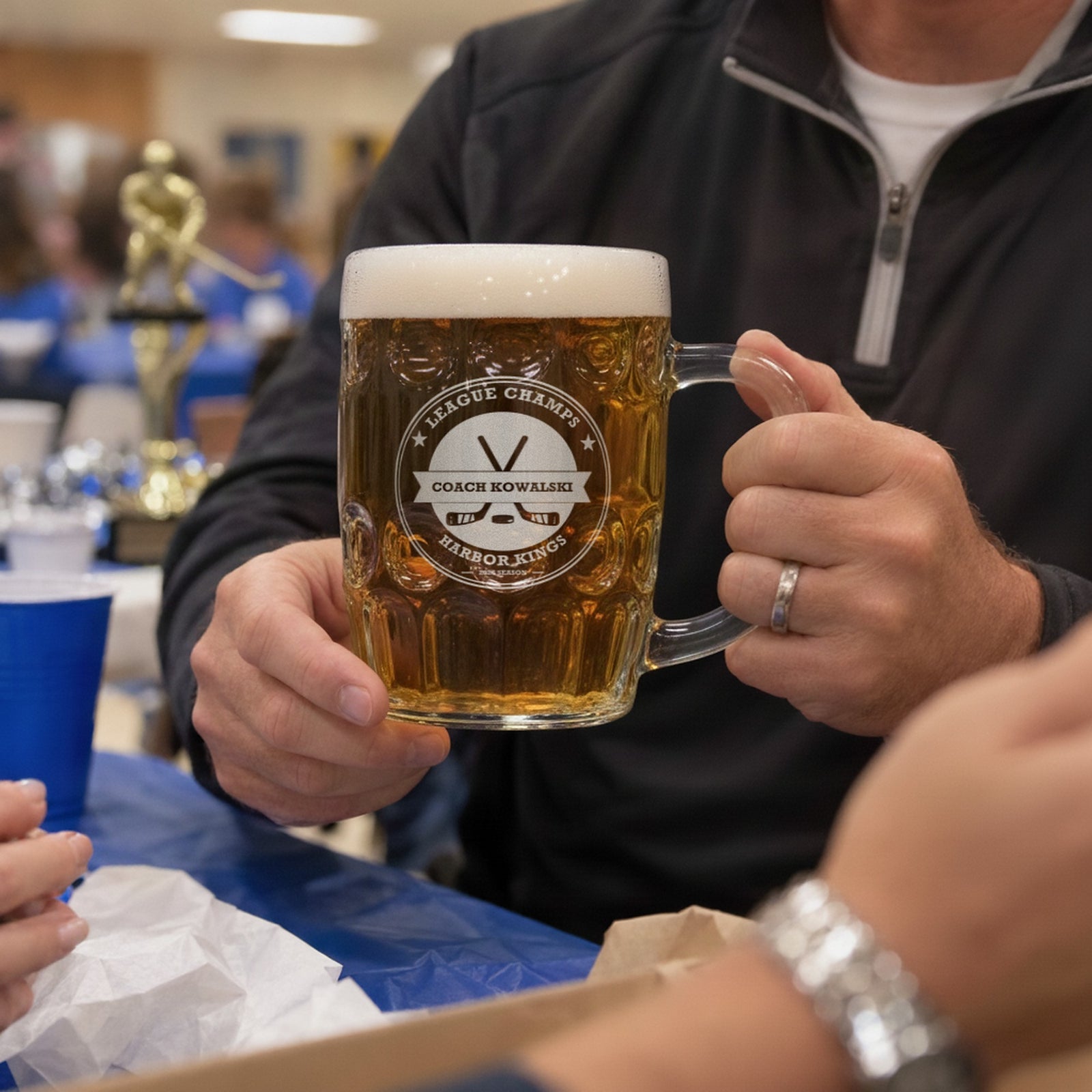 Coach holding a hockey stein engraved League Champs and Coach Kowalski for Harbor Kings at the end-of-season team banquet