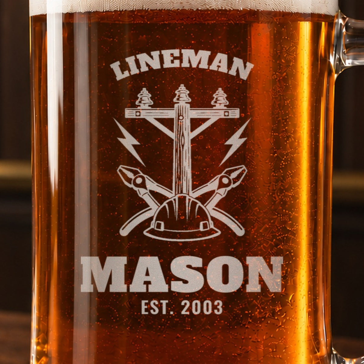 Close-up of the frosted engraving on the lineman beer stein, a utility pole, a hard hat and crossed lineman pliers: Lineman, Mason, Est. 2003