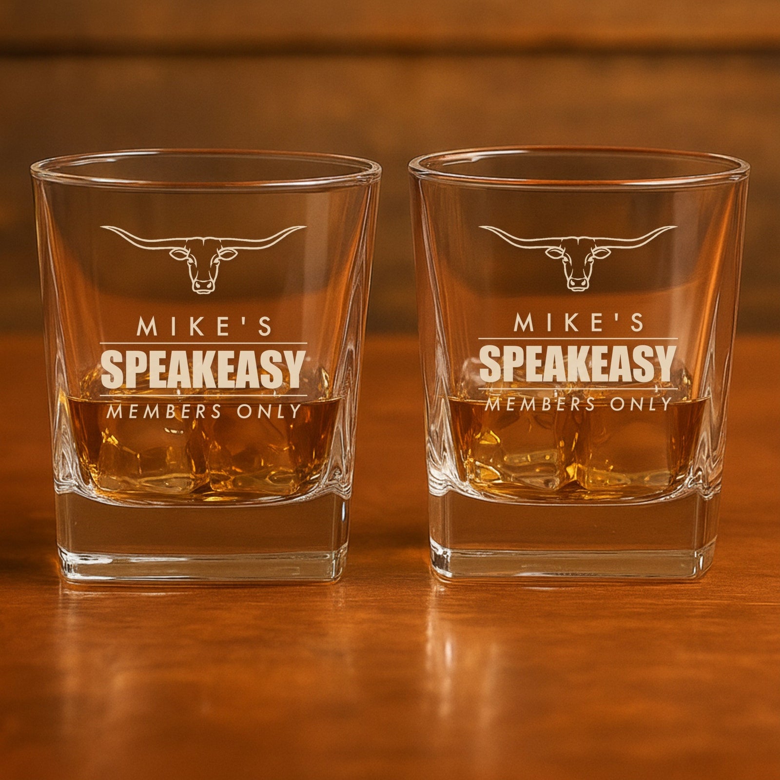 A pair of engraved whiskey glasses reading Mike's Speakeasy, Members Only under a longhorn, a matching personalized set for his bar