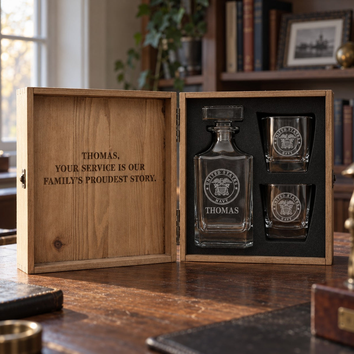 Military decanter set in an open wood box, the decanter and two glasses engraved with the Navy seal and a family thank you on the lid, one of our unique gifts for veterans