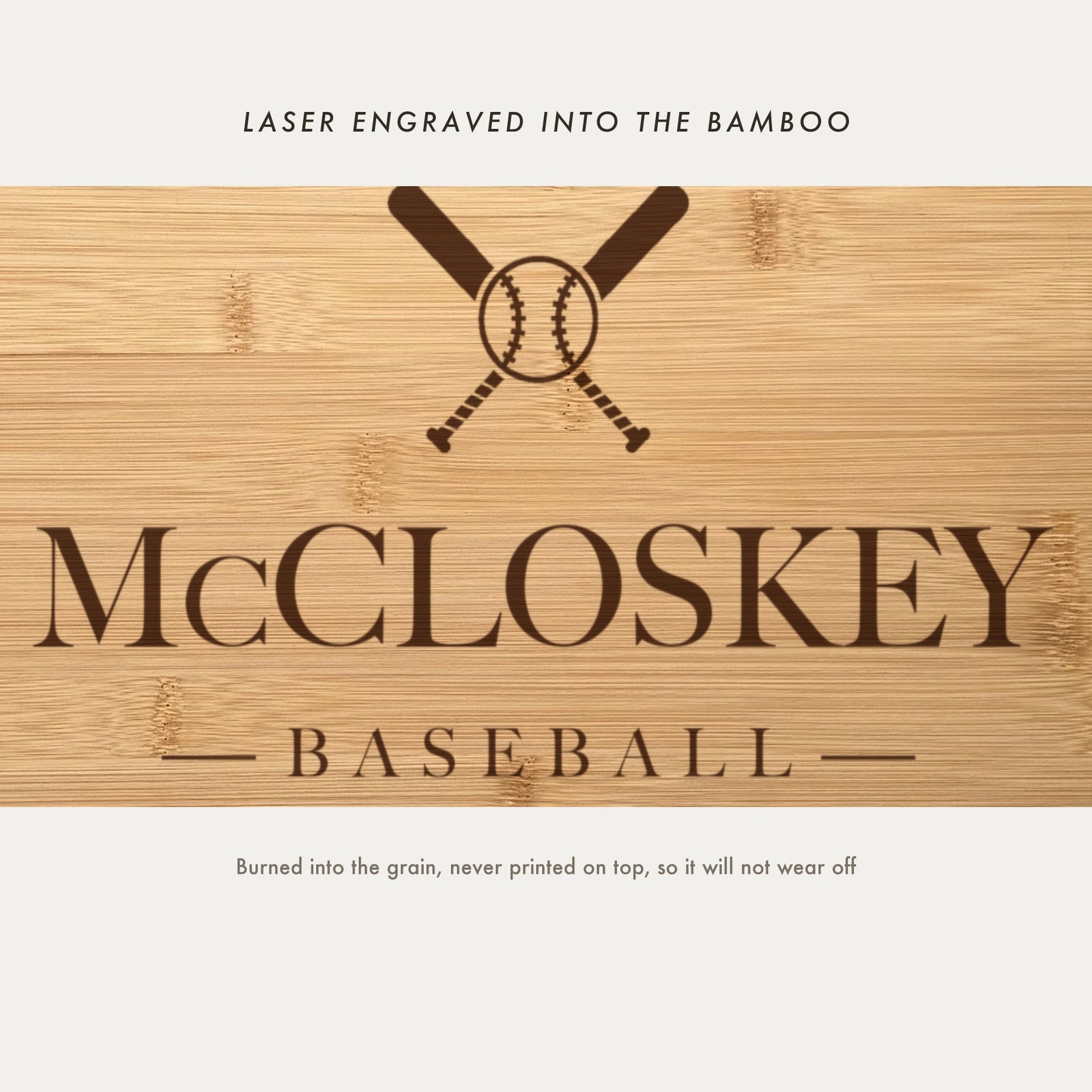 Close view of the crossed baseball bats and stitched ball laser engraved into the bamboo grain above the name in a high contrast serif.