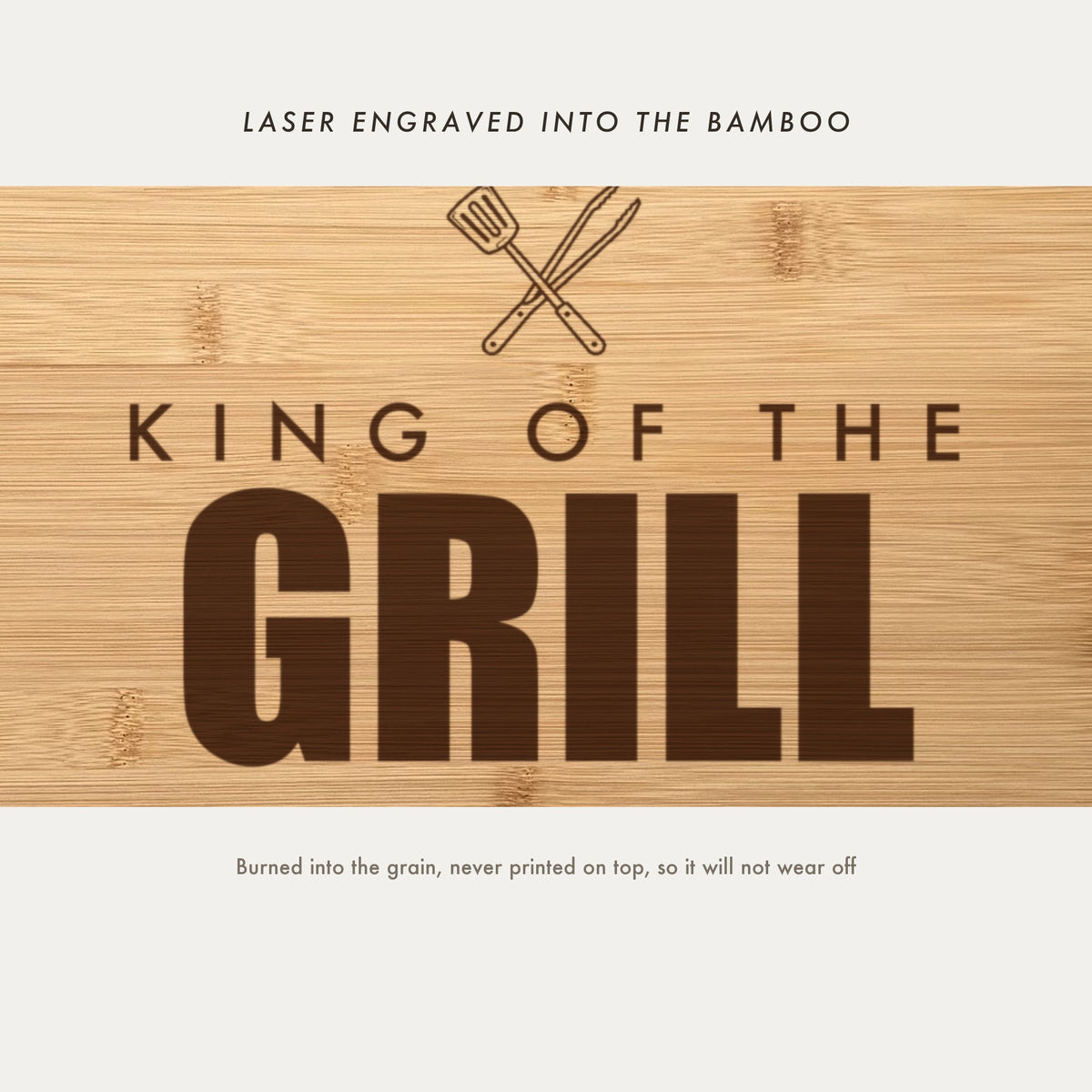 Close view of the crossed spatula and tongs with King of the Grill laser engraved into the bamboo grain in heavy block capitals.