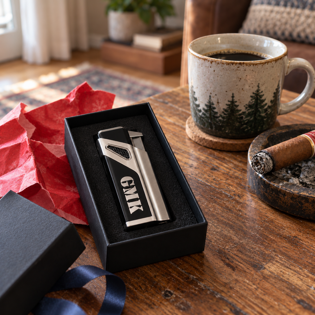 Personalized cigar lighter engraved GMK resting in its black gift box with red wrapping paper, a cup of coffee and a cigar on the table