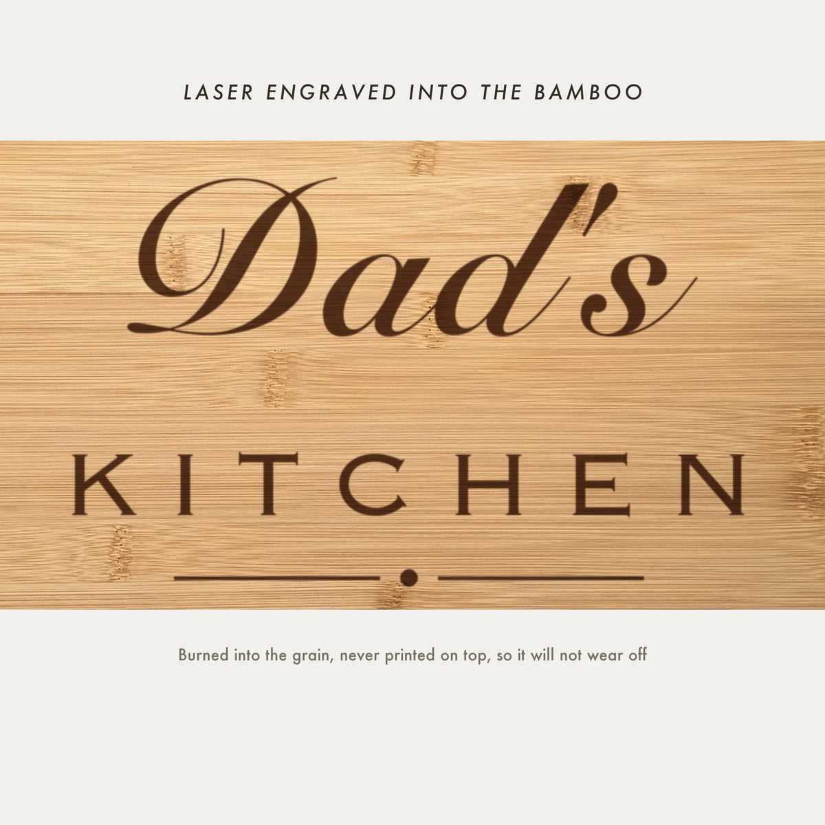 Close view of Dad's Kitchen laser engraved into the bamboo grain, showing the script name above the spaced capitals and the kids names beneath.