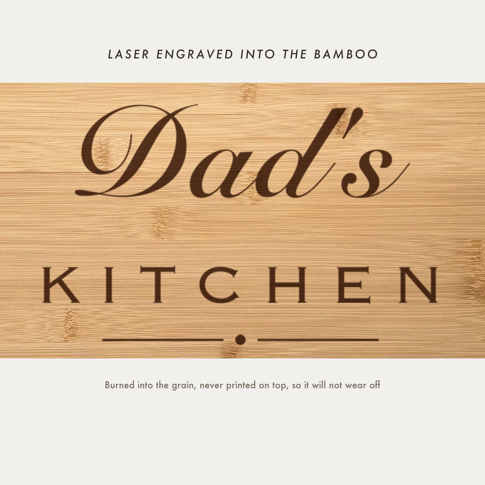 Close view of Dad's Kitchen laser engraved into the bamboo grain, showing the script name above the spaced capitals and the kids names beneath.