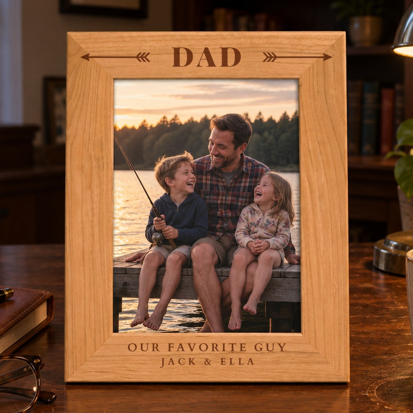 Personalized dad picture frame in red alder engraved Dad between feathered arrows with Our Favorite Guy and Jack & Ella, holding a photo of a dad with his kids on a lake dock