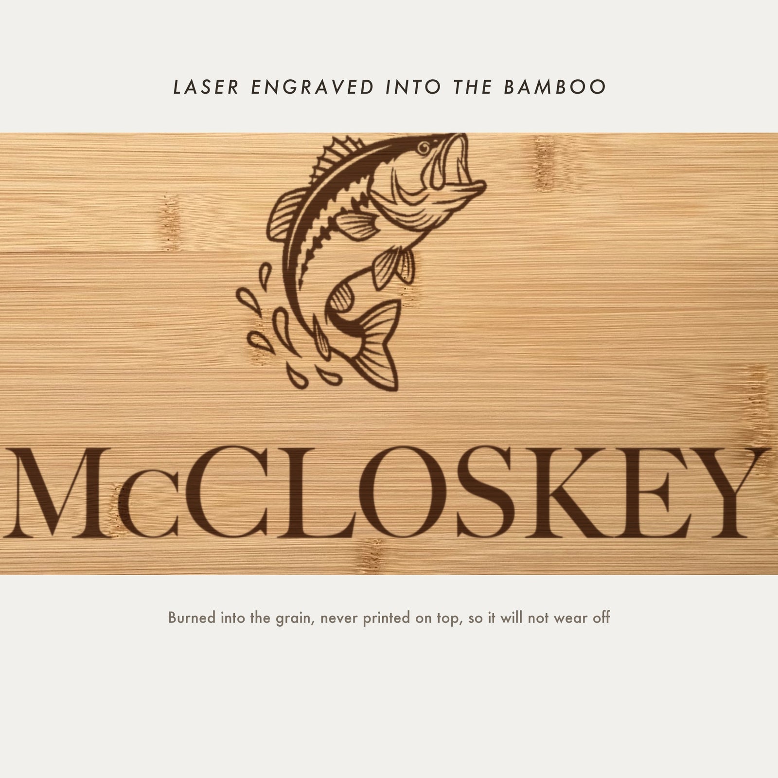 Close view of the leaping bass and water splash laser engraved into the bamboo grain above the family name in a high contrast serif.