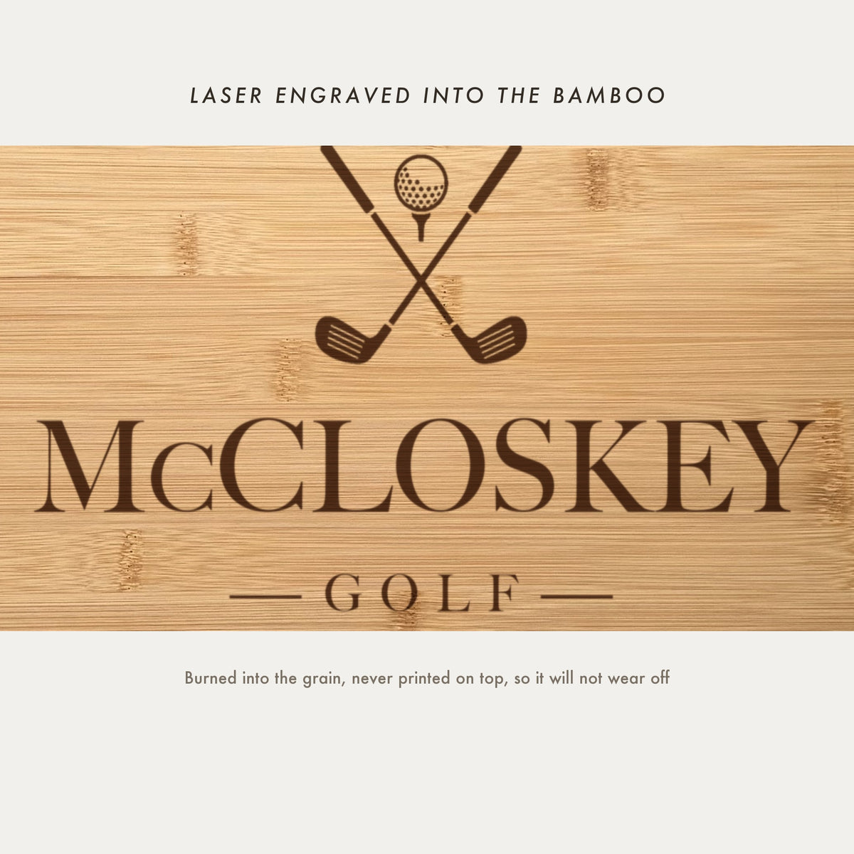 Close view of the crossed golf clubs and ball on a tee laser engraved into the bamboo grain above the family name in a high contrast serif.