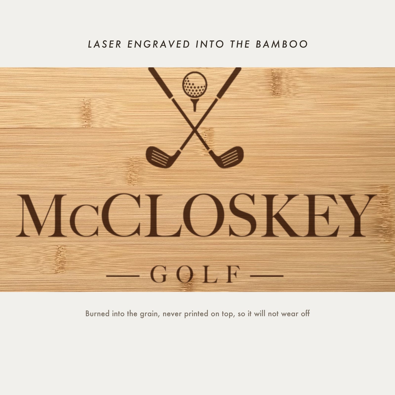 Close view of the crossed golf clubs and ball on a tee laser engraved into the bamboo grain above the family name in a high contrast serif.
