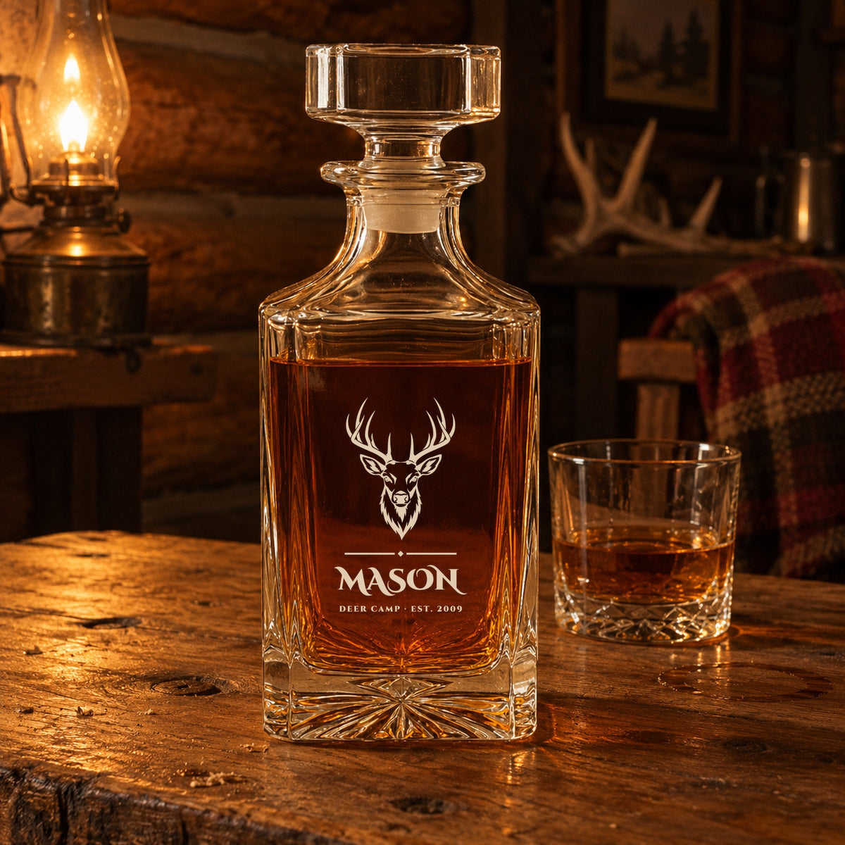 Personalized hunting whiskey decanter on a cabin table by an oil lamp, engraved with a buck over the name Mason, a gift for hunters and men