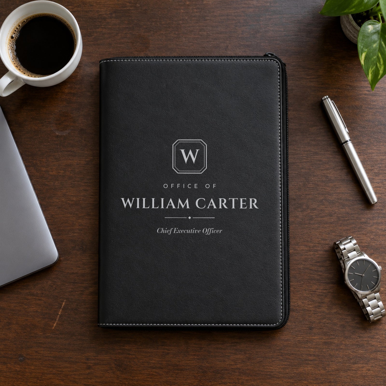 Personalized padfolio for men in black, engraved in silver with a W monogram plate, Office of, William Carter and Chief Executive Officer on a walnut desk