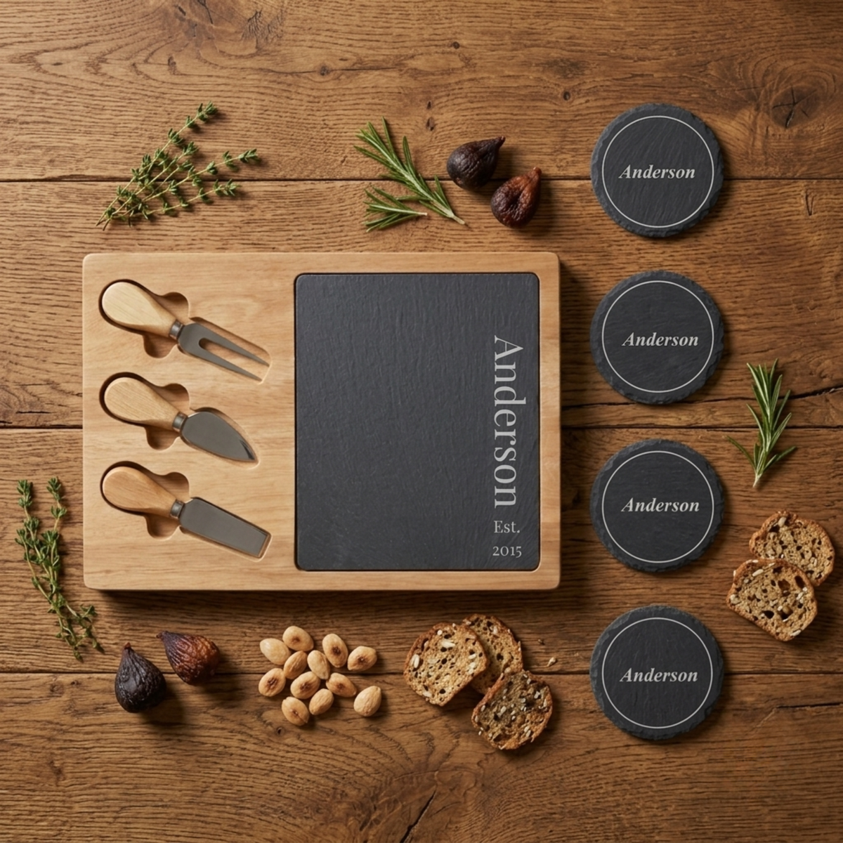 Personalized slate cheese board and coaster set engraved with the last name Anderson and Est. 2015, paired with three wood-handled cheese knives on an acacia board