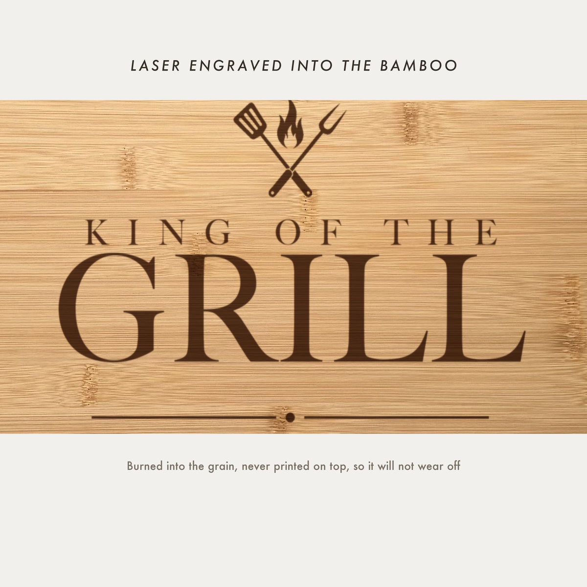 Close view of the crossed spatula and fork with a flame laser engraved into the bamboo grain above King of the Grill in a high contrast serif.