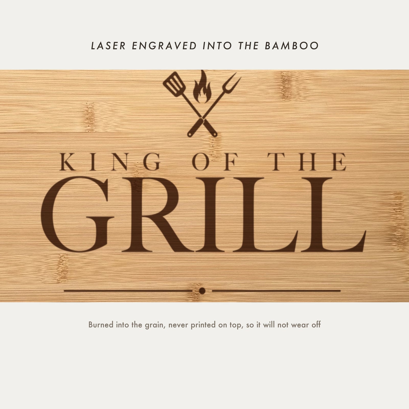 Close view of the crossed spatula and fork with a flame laser engraved into the bamboo grain above King of the Grill in a high contrast serif.